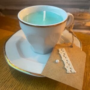 Bougie colorée vert turquoise avec mèche de coton dans sa tasse avec la soucoupe.