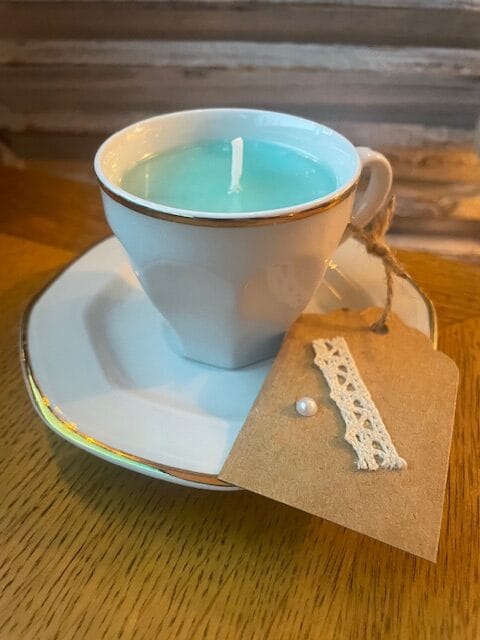 Bougie colorée vert turquoise avec mèche de coton dans sa tasse avec la soucoupe.