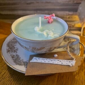 Bougie colorée vert pastel avec quelques fleurs séchées dans sa tasse avec la soucoupe. 100gr