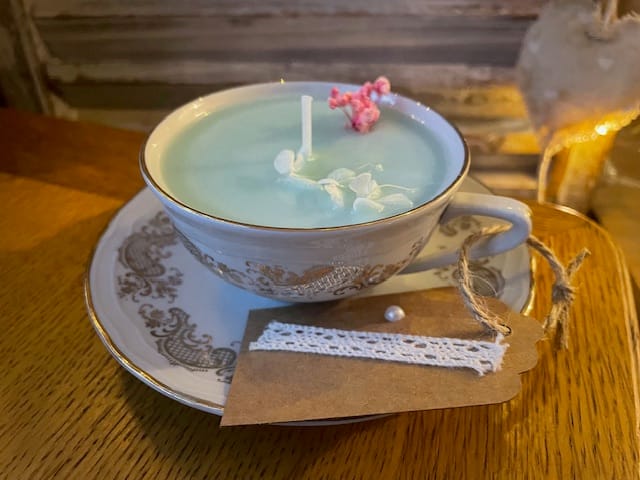 Bougie colorée vert pastel avec quelques fleurs séchées dans sa tasse avec la soucoupe. 100gr